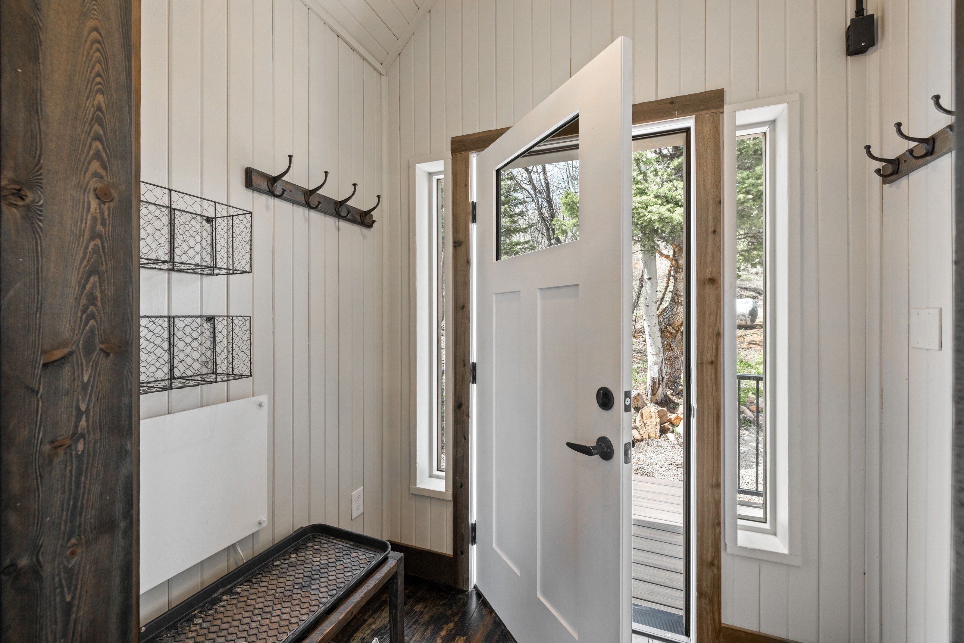 Foyer entrance with wood walls, healthy amount of natural light, dark wood finished floors, and vaulted ceiling