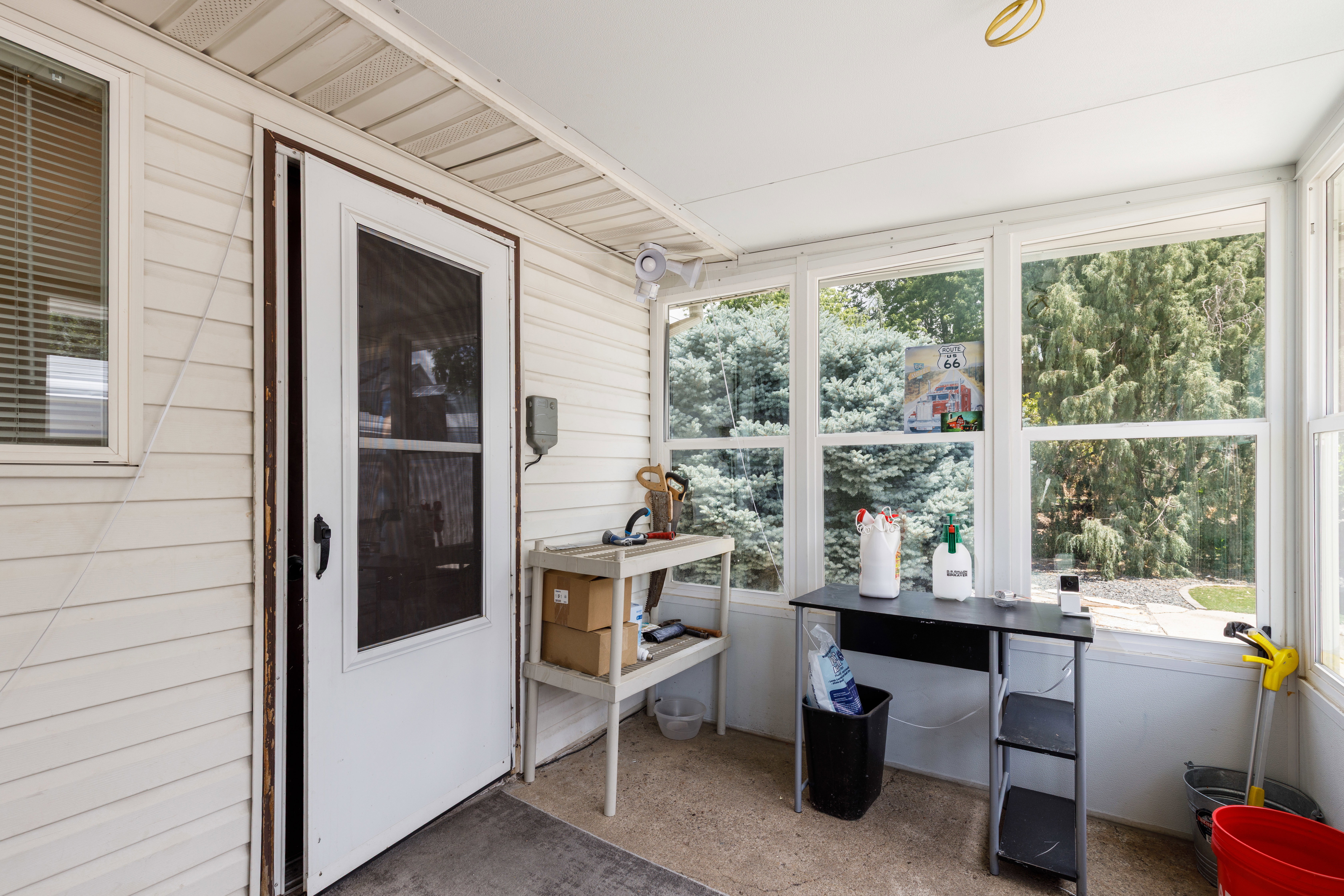 Enclosed porch featuring multiple windows, vinyl siding exterior, and a white screen door