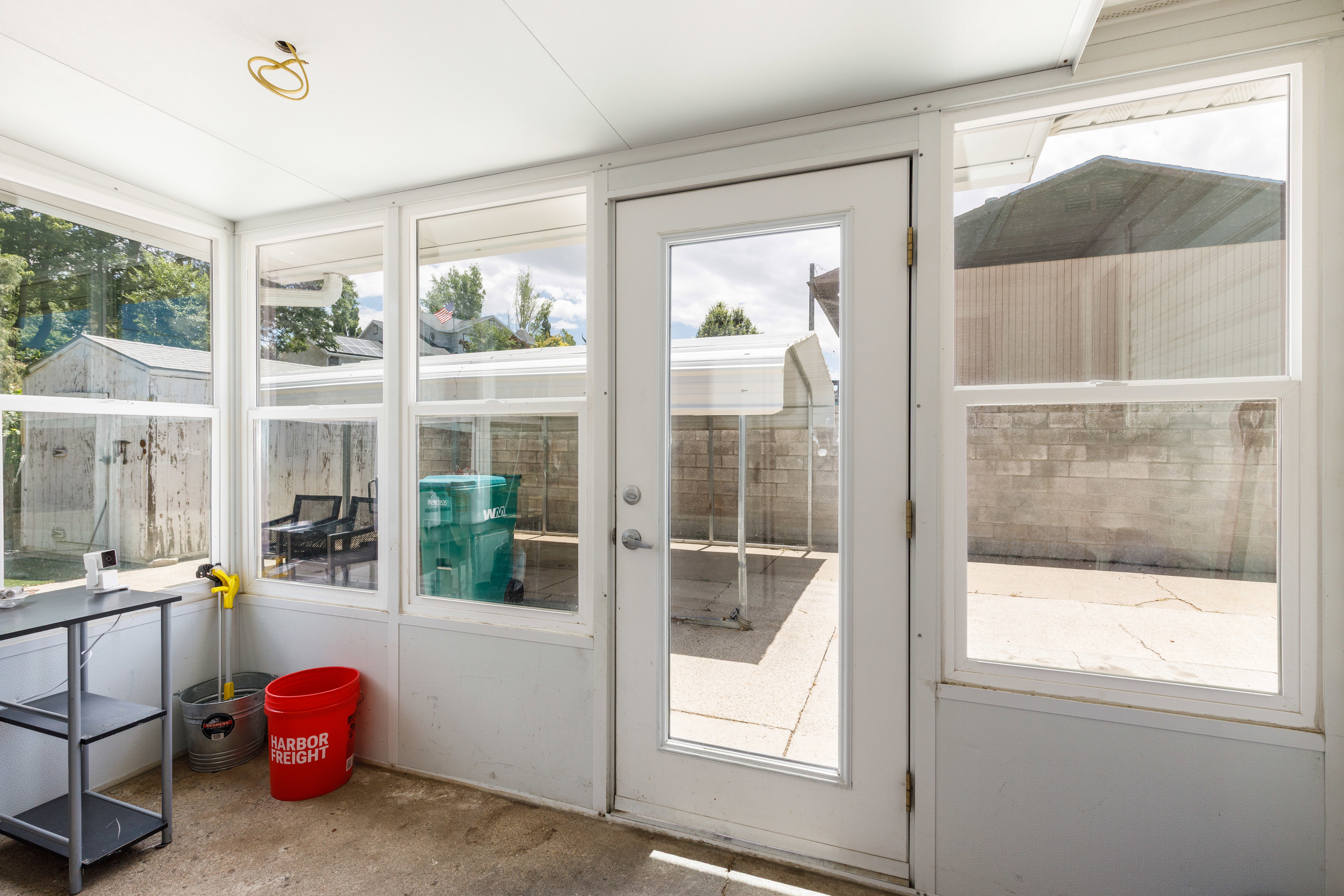 Enclosed sunroom with multiple large windows, a full-lite exterior door, and a textured concrete floor