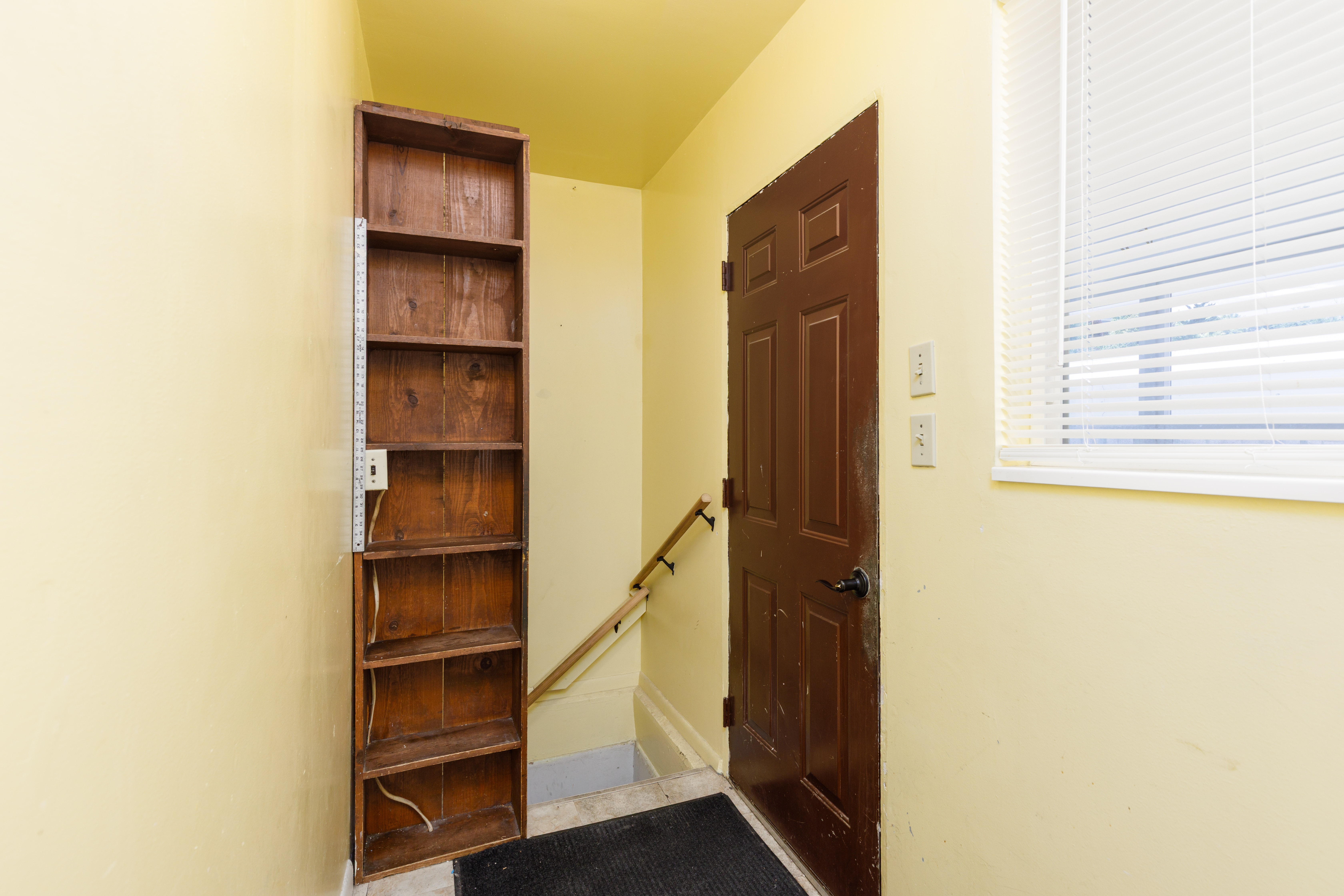 Entryway featuring a wood panel door, natural light from a window with blinds, and built-in wood shelving