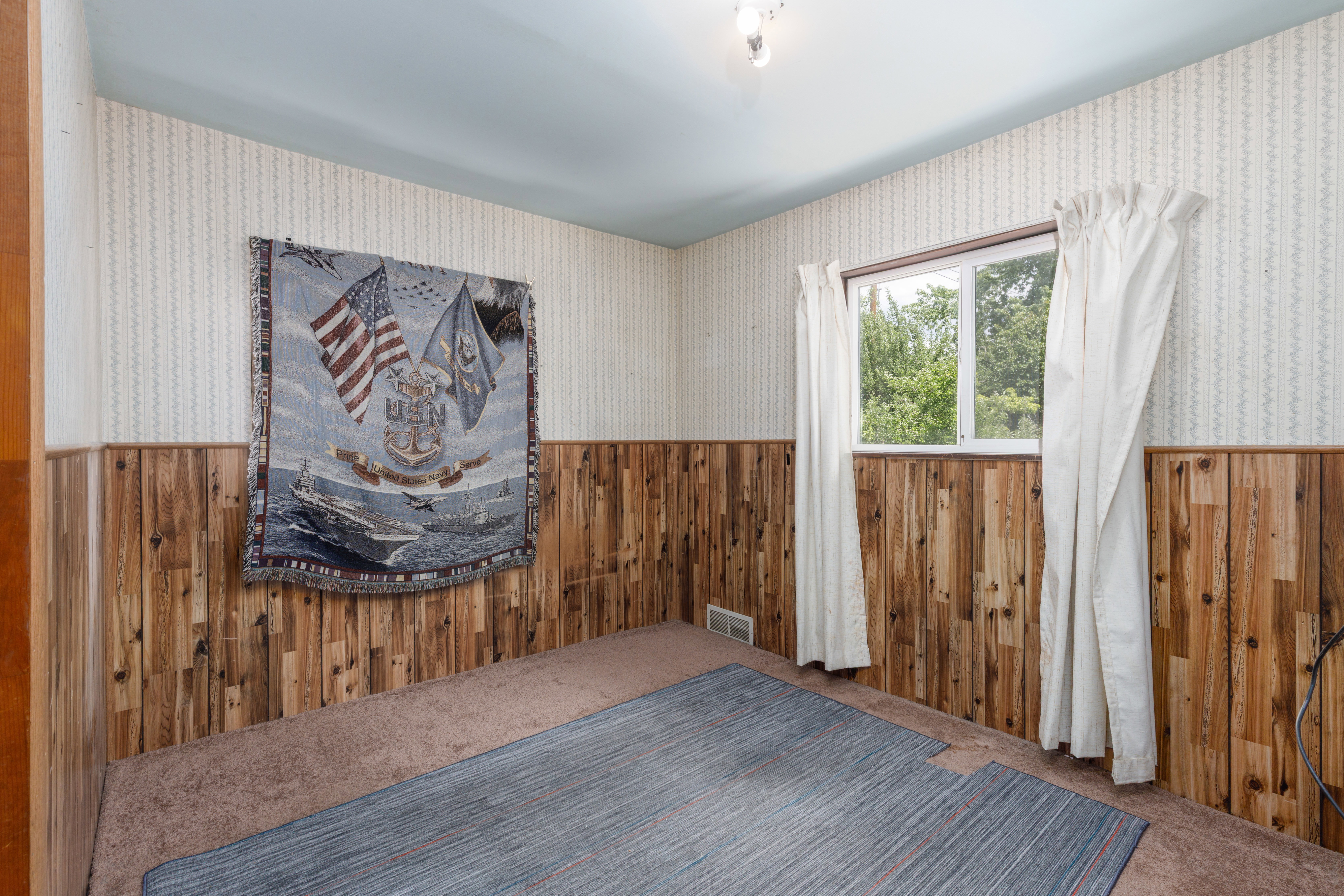 Room featuring wood paneling, wall-to-wall carpeting, and a window with natural light
