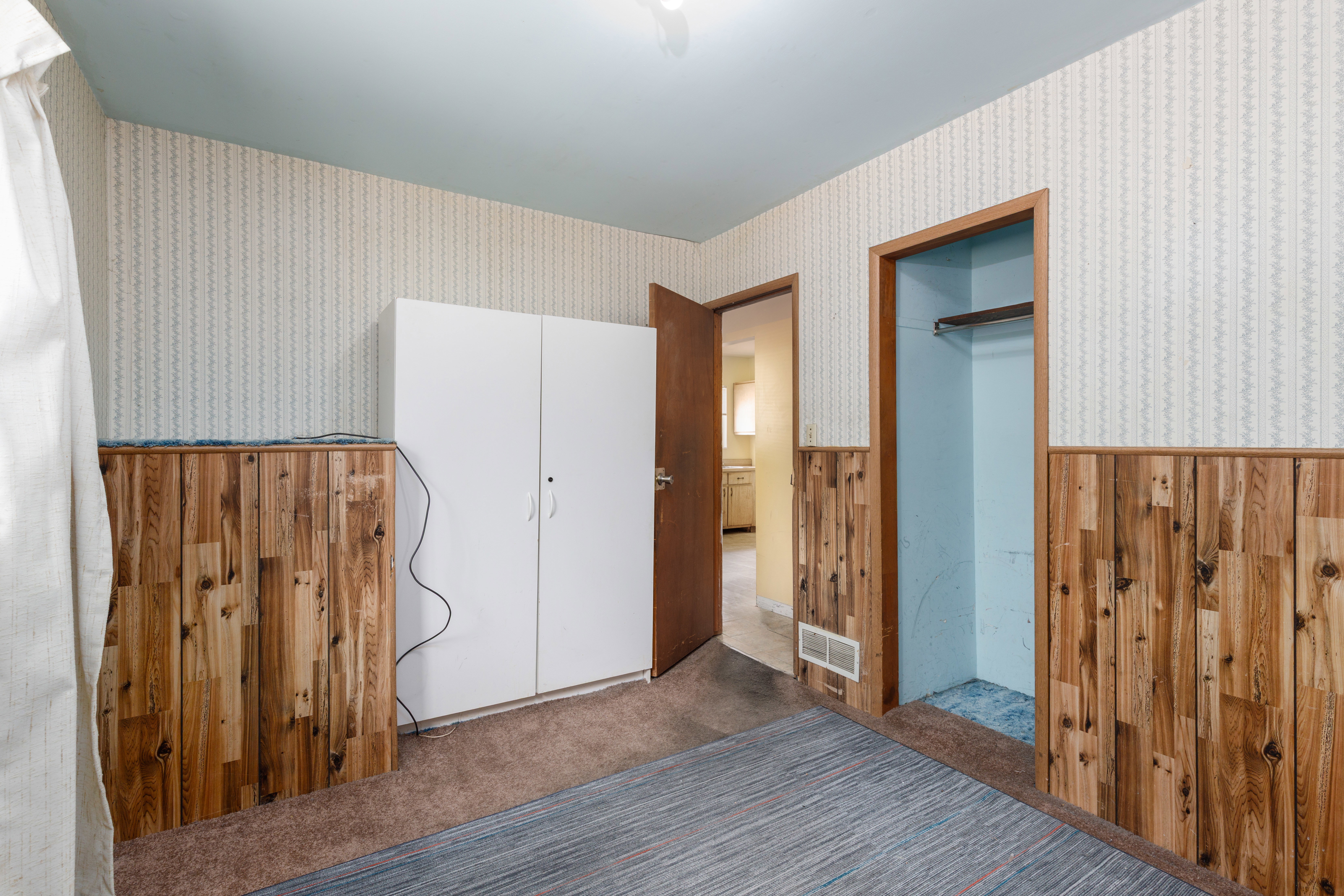Interior room featuring wood paneling, patterned wallpaper, and light blue ceiling