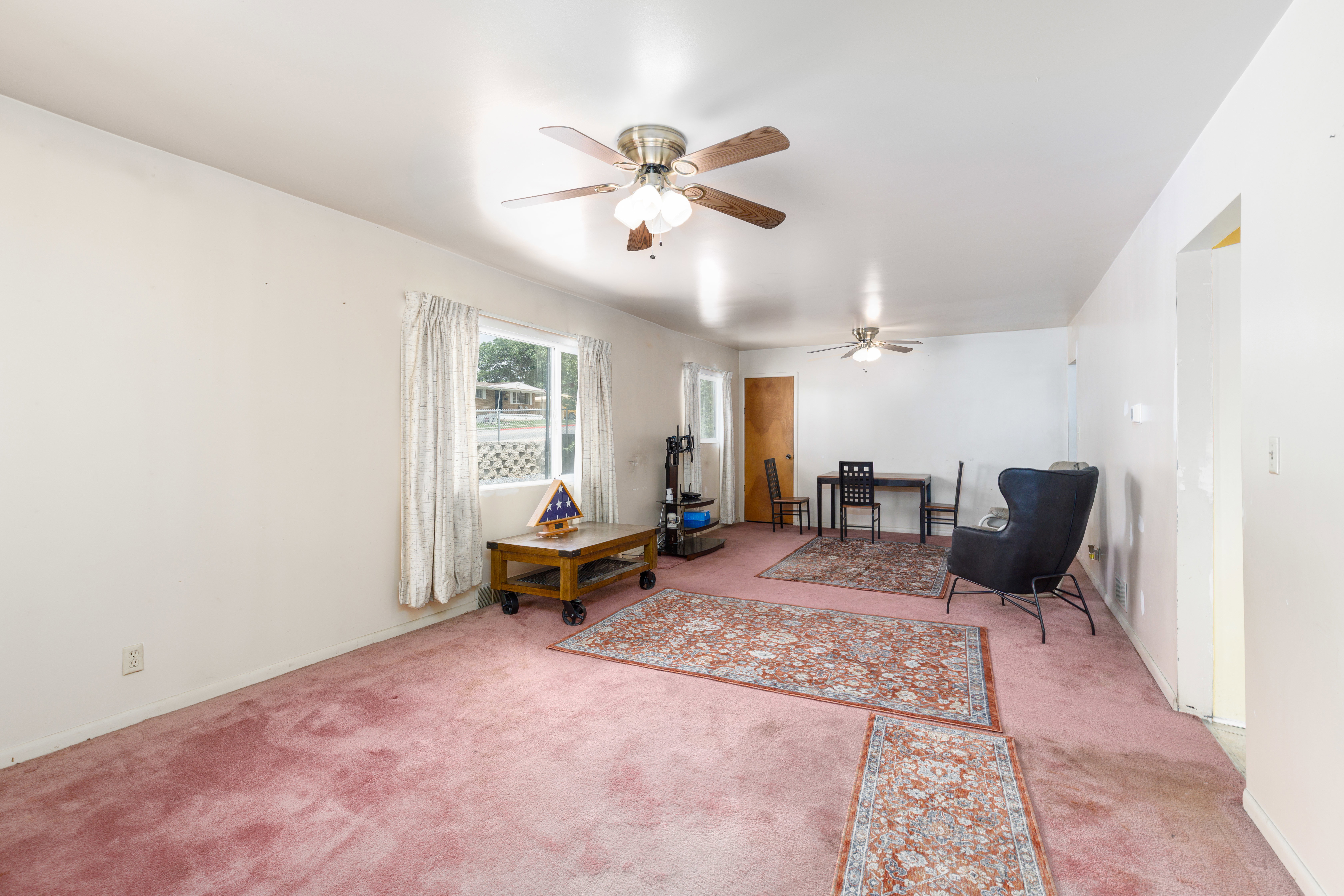 Bright interior space featuring a window with natural light, two ceiling fans, and a solid core door