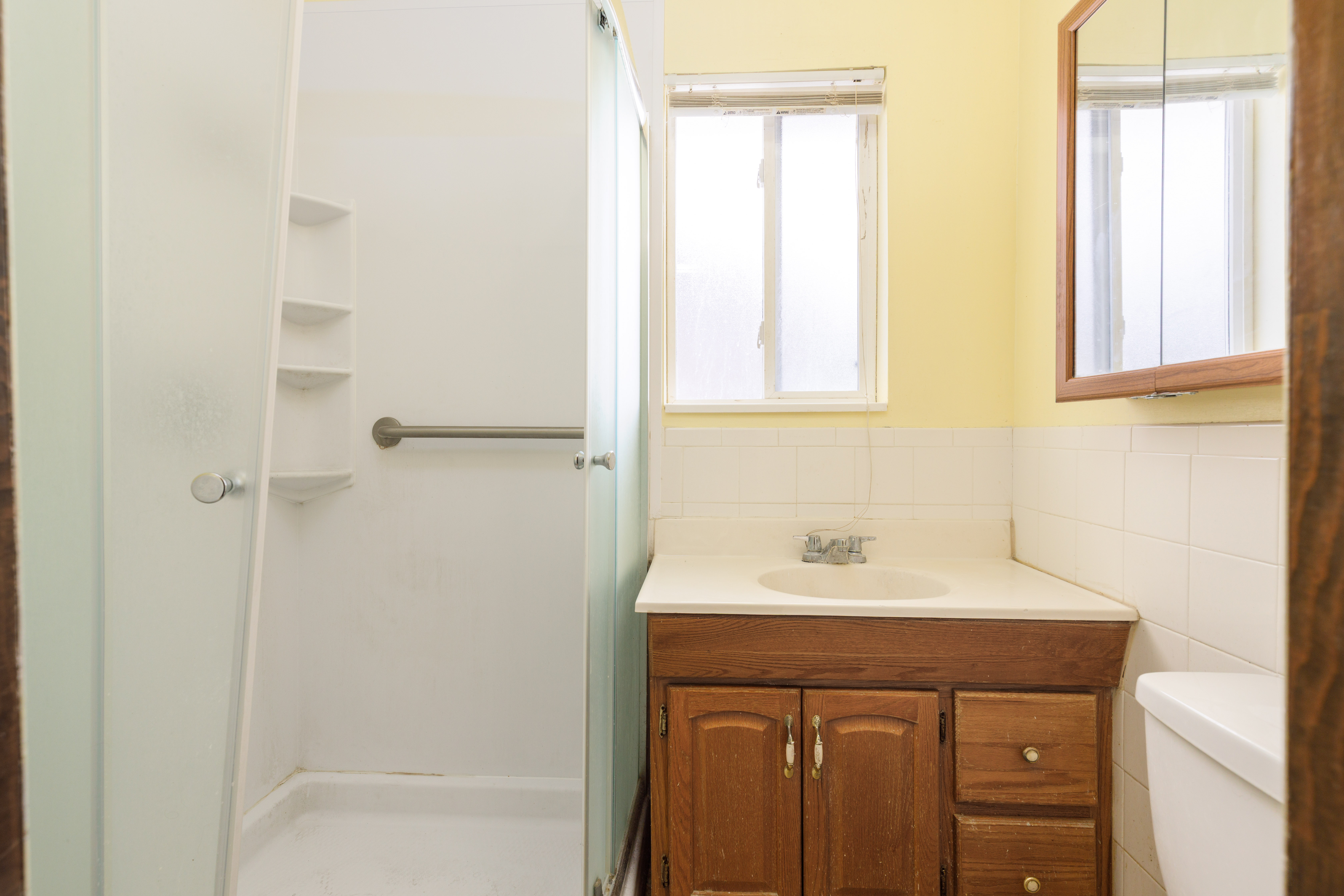 Bathroom featuring a wood vanity with integrated sink, white tile backsplash, and a medicine cabinet with a wood frame
