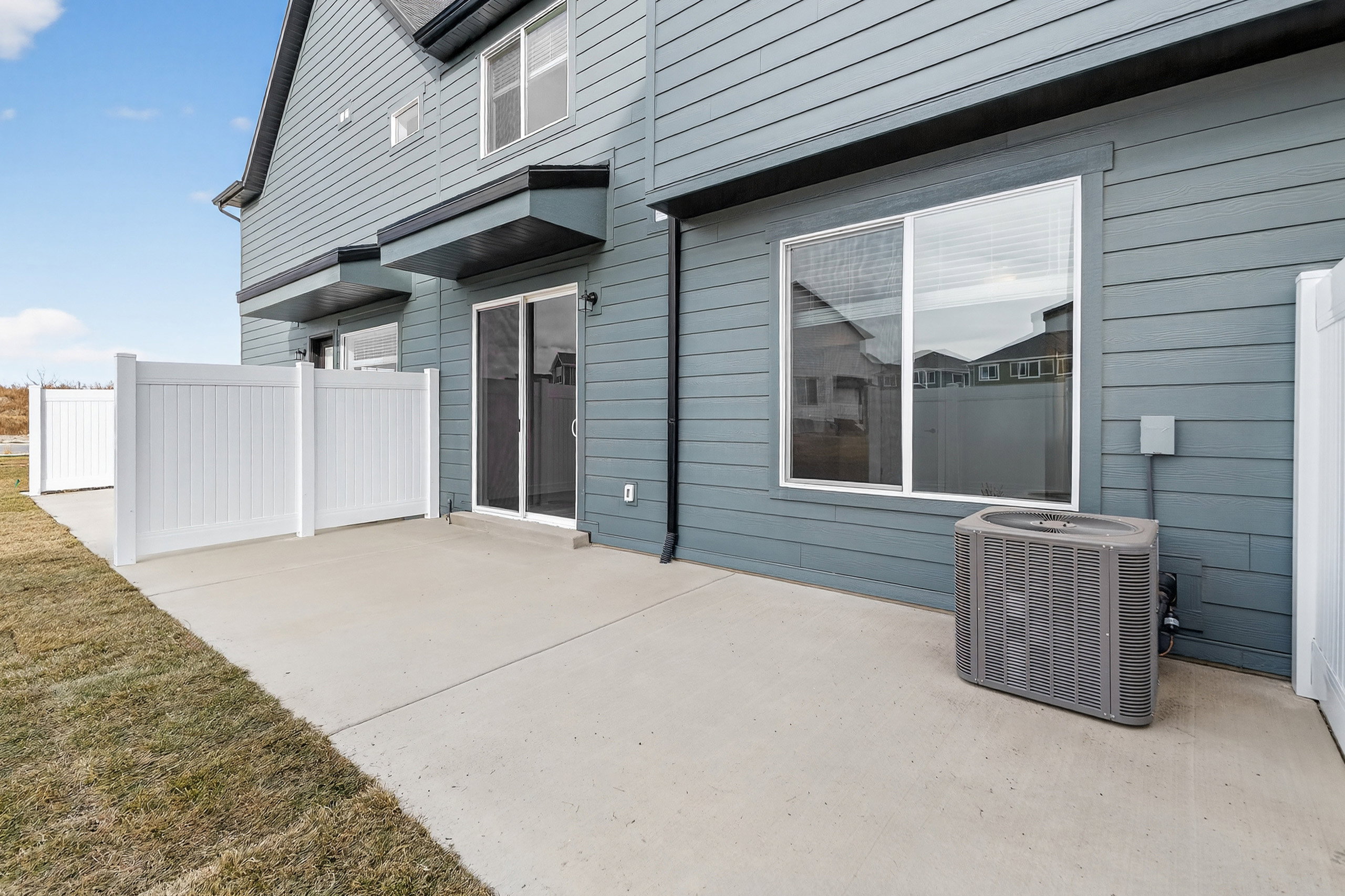 Exterior featuring light blue horizontal siding, a concrete patio, and a white vinyl privacy fence