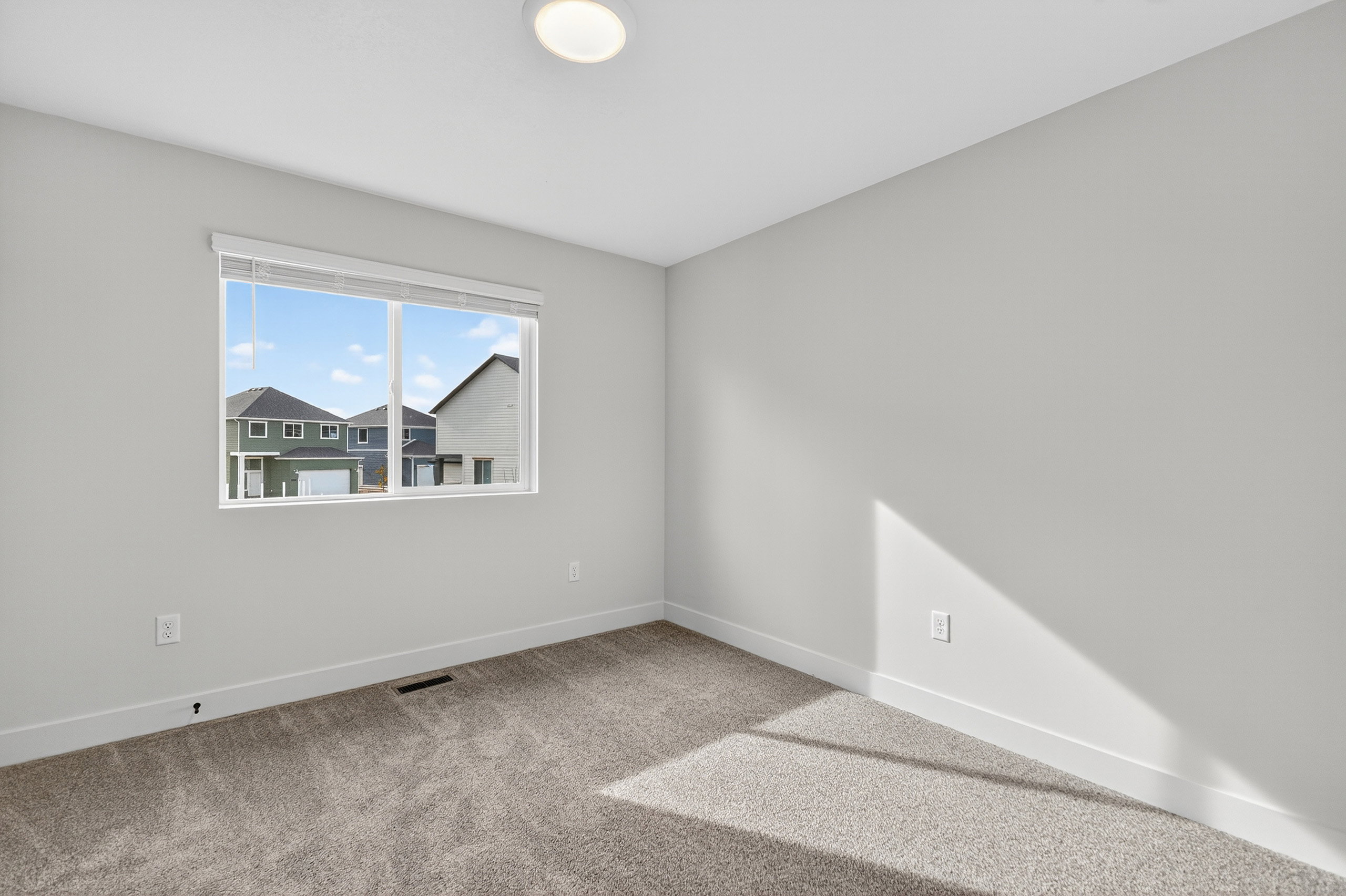 Carpeted room with a double-paned window, neutral wall paint, white trim, and a flush mount ceiling light