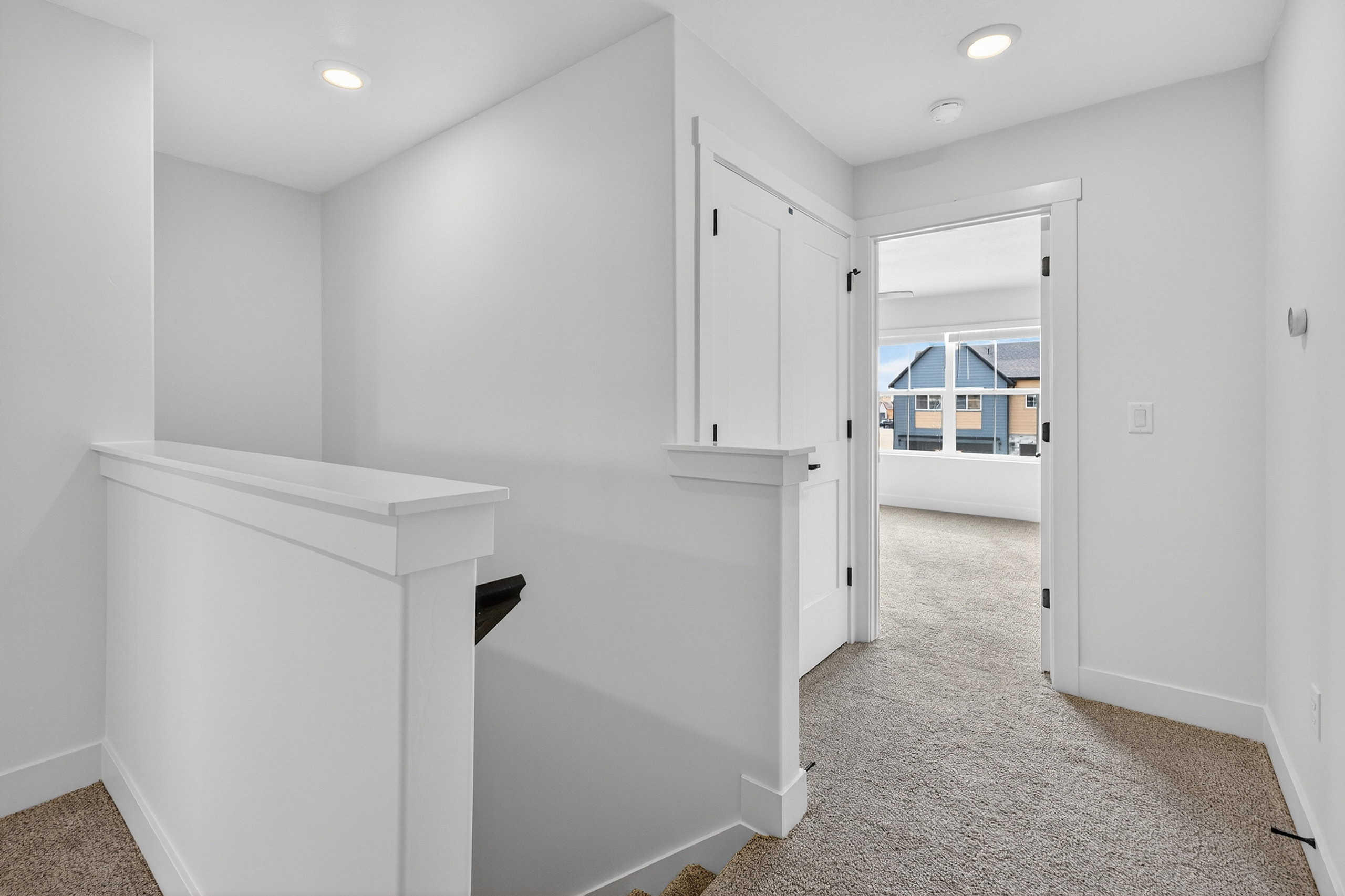 Upper-level landing featuring neutral carpeting, recessed lighting, and crisp white trim