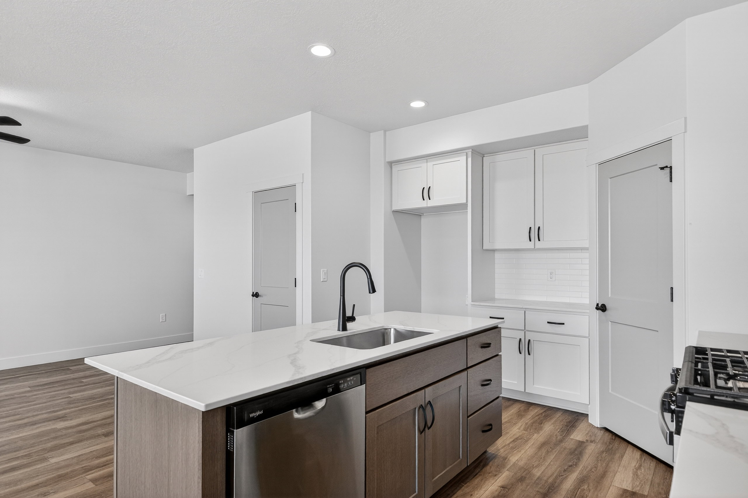Kitchen island featuring a stainless steel sink, black faucet, and built-in dishwasher