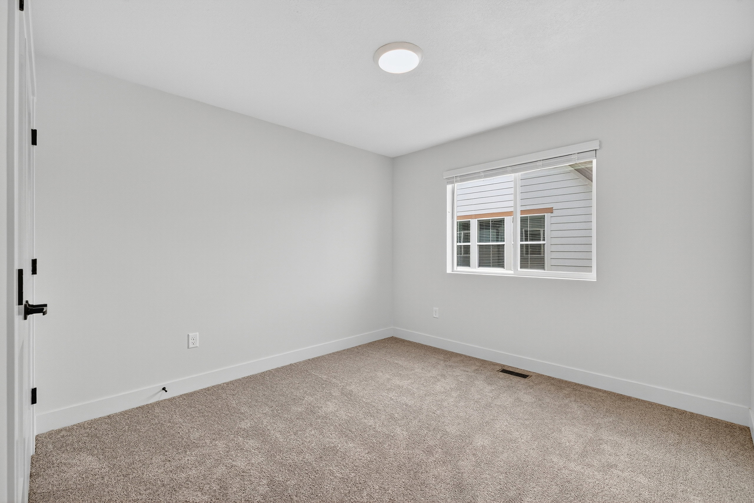 Bedroom featuring neutral-toned carpeting, light-colored walls, and a single window with blinds