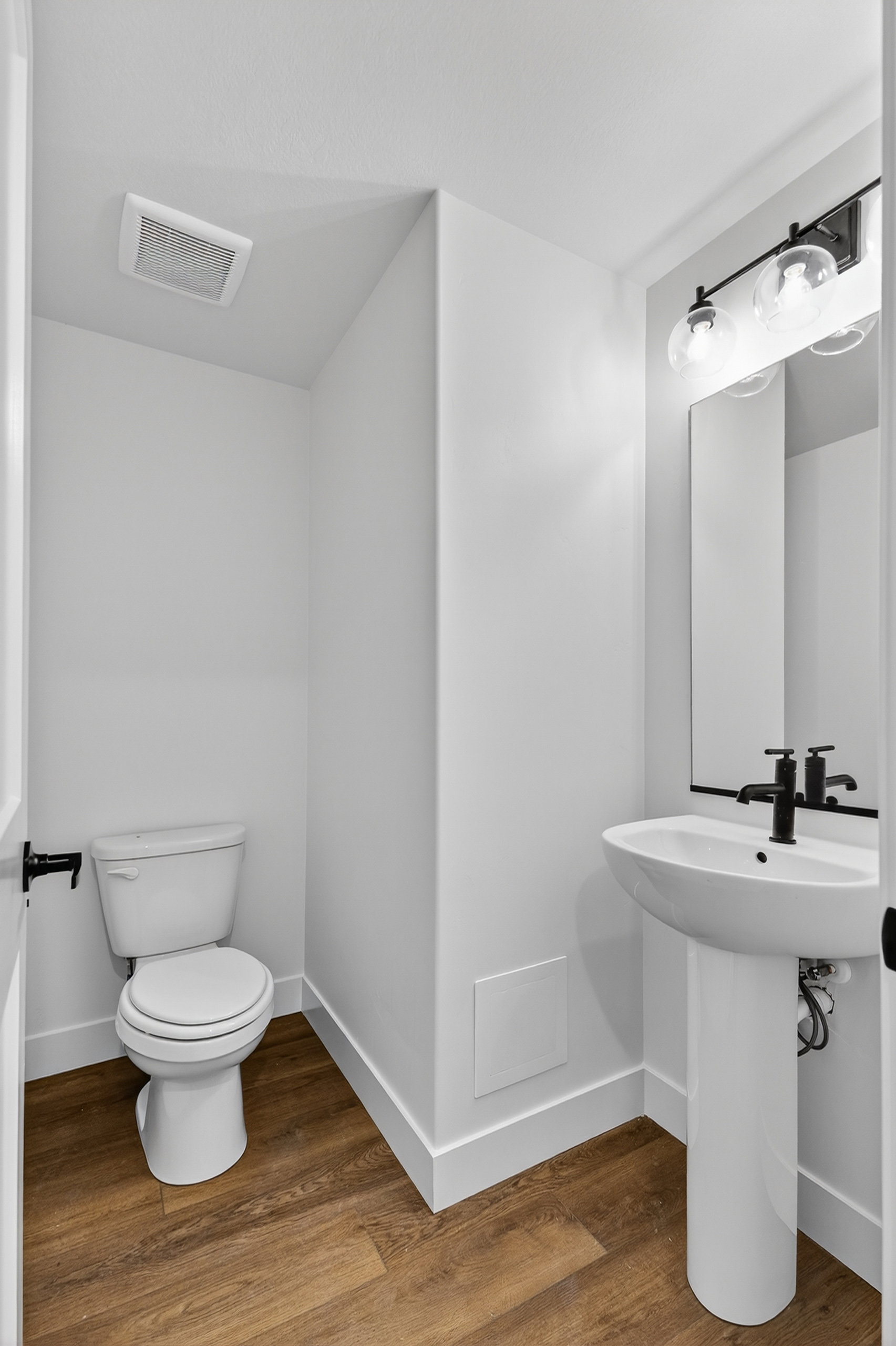 Pedestal sink with matte black faucet and mirror