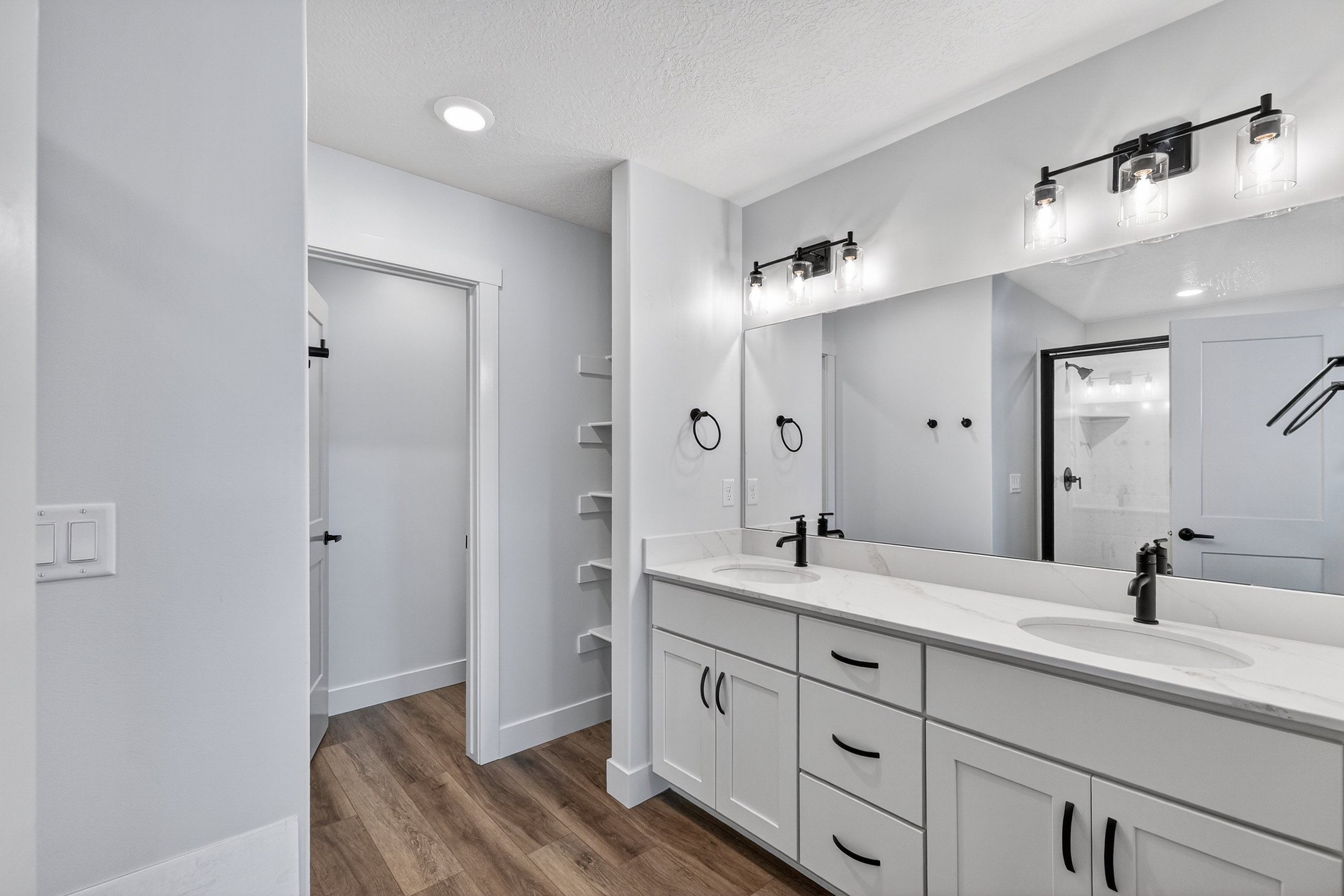 Bathroom vanity featuring a dual-sink design with undermount sinks, stone countertops, and matte black fixtures