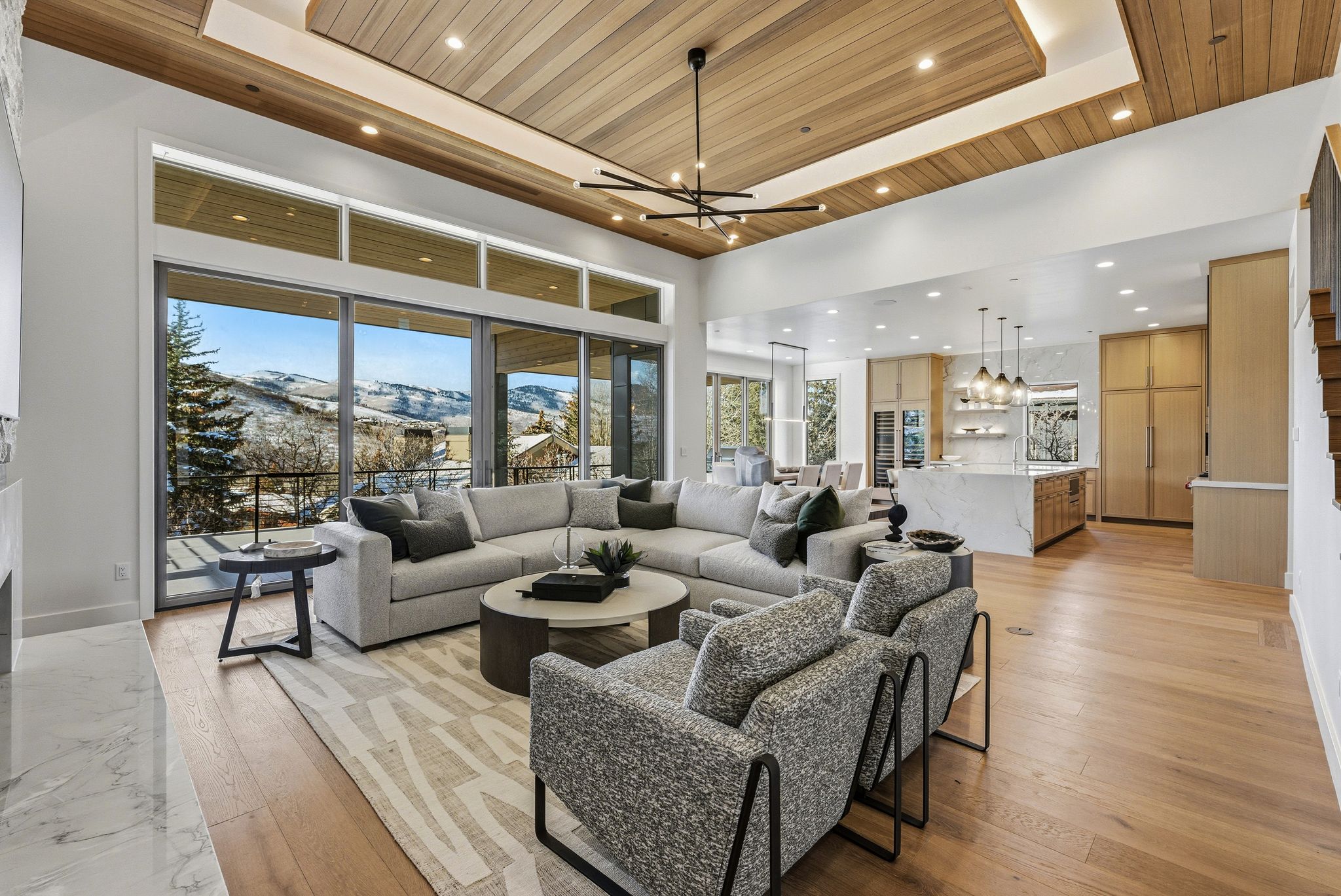 Open-concept living space featuring expansive glass doors, wood-finish flooring, and a coffered wood-panel ceiling