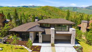 Contemporary exterior featuring a stone and dark wood facade, multiple rooflines with dark metal accents, and a two-car garage