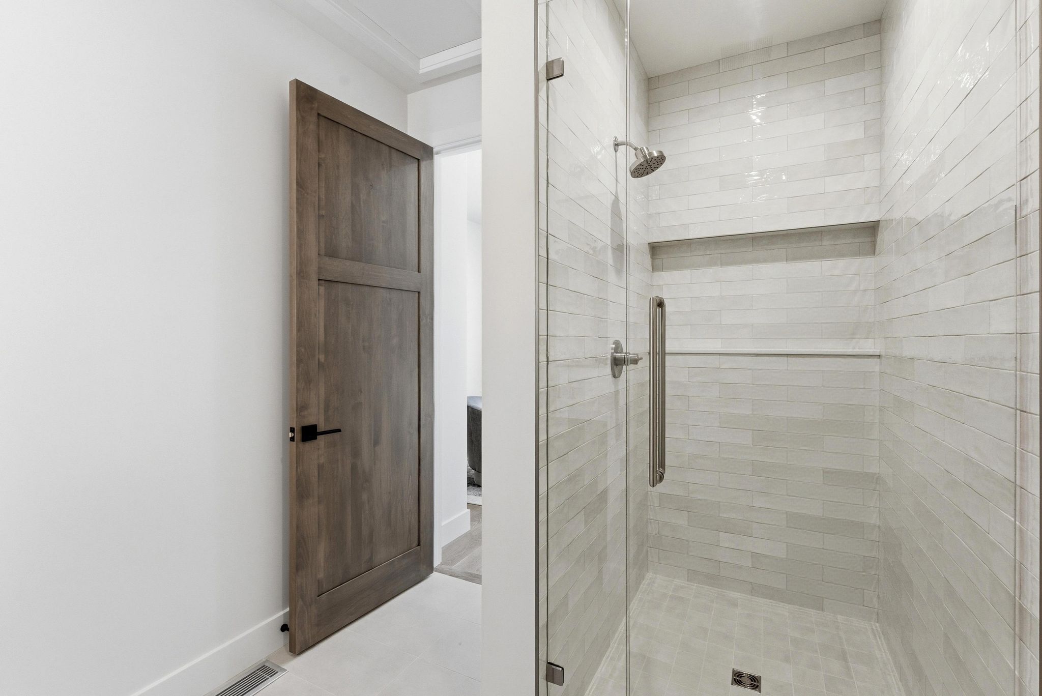 Walk-in shower featuring subway tile surround, recessed shelf, glass enclosure, and brushed nickel fixtures