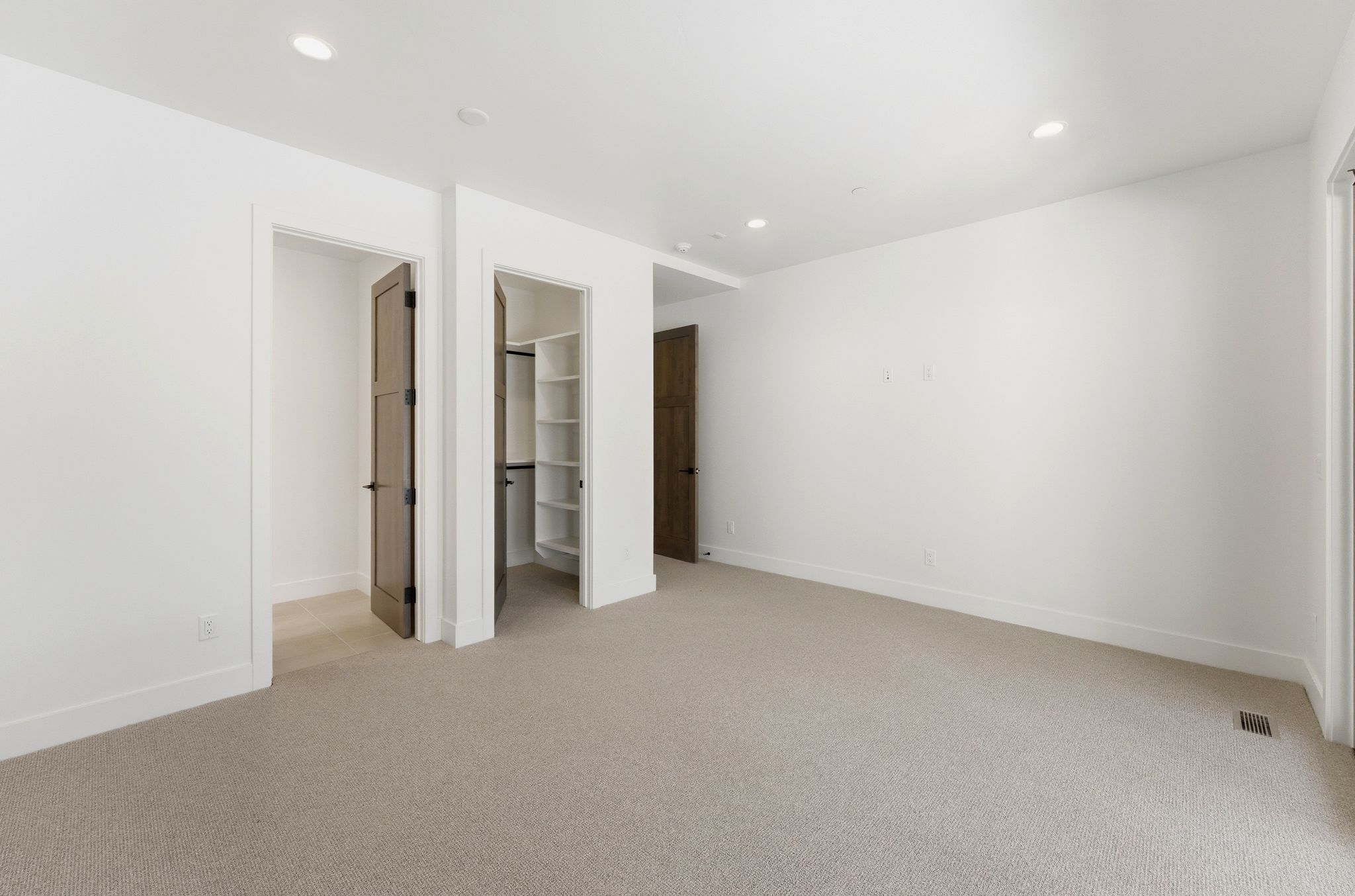 Spacious room featuring light-colored carpeting, white walls, and recessed lighting