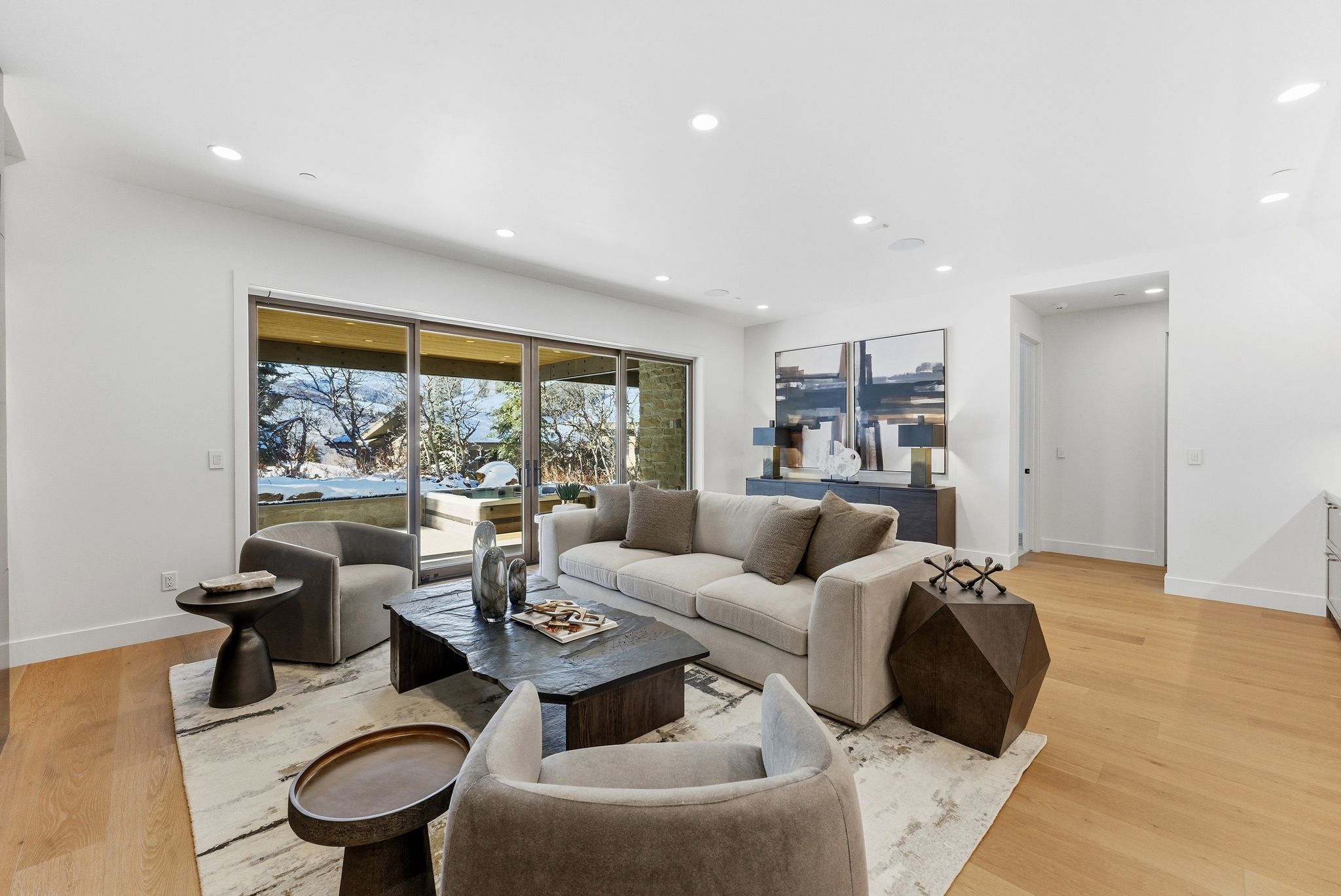 Spacious room featuring light wood-finish flooring, recessed lighting, and a large multi-panel sliding glass door