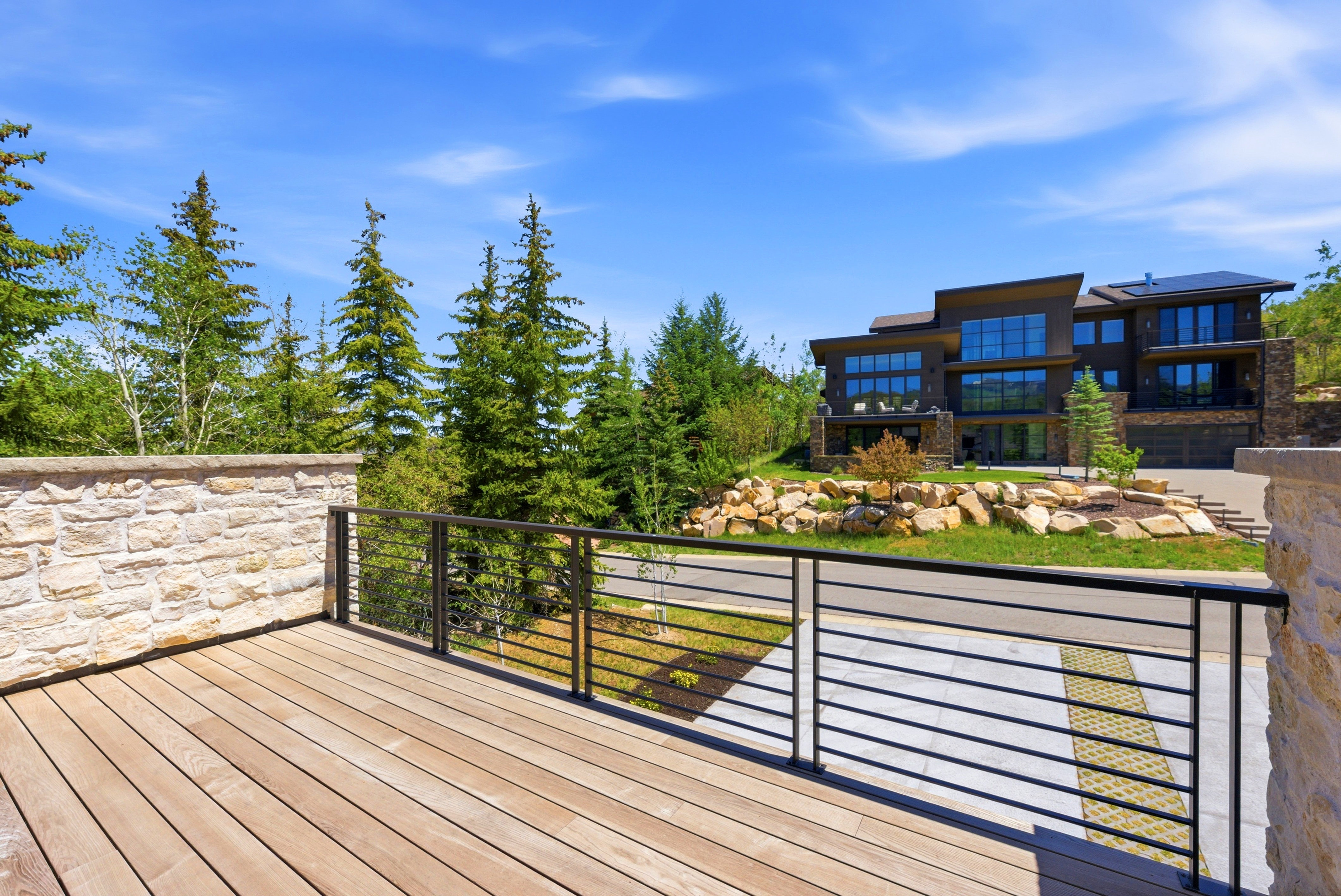 Expansive outdoor deck featuring wood-finish flooring and a contemporary metal railing system