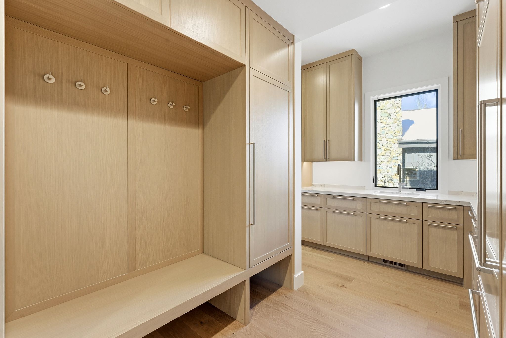 Built-in wood-finish cabinetry featuring integrated hooks, a bench, and additional storage