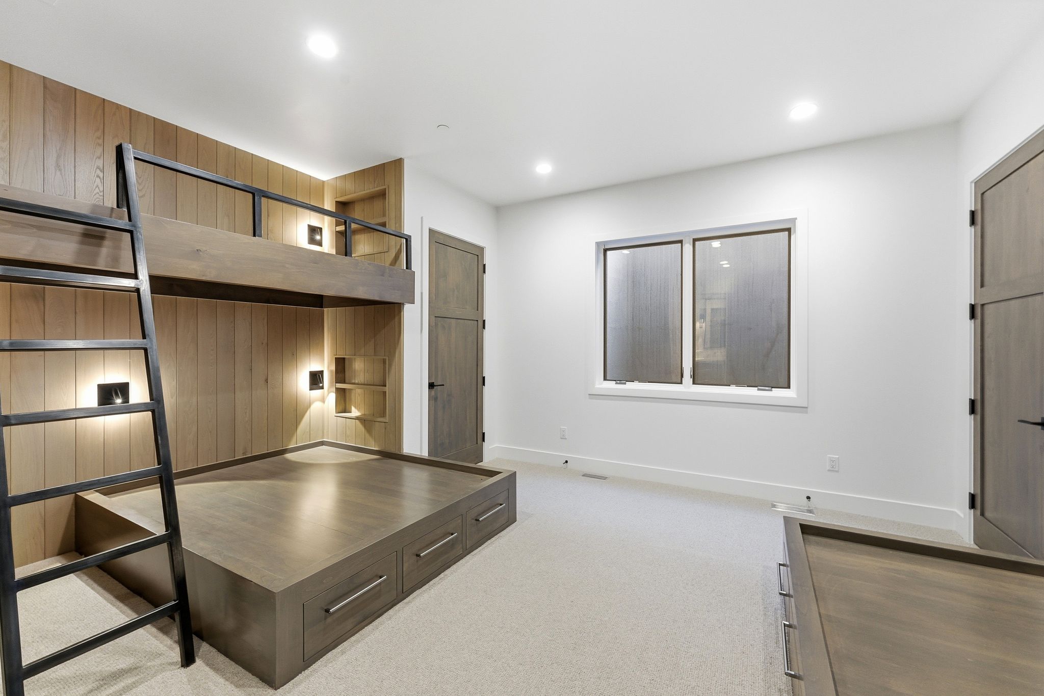 Built-in bunk bed system with integrated lighting and shelving, featuring wood paneling and a coordinated lower platform bed with drawer storage