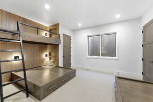 Built-in bunk bed system with integrated lighting and shelving, featuring wood paneling and a coordinated lower platform bed with drawer storage