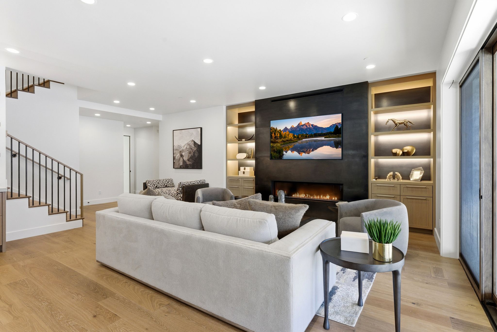 Living area featuring wide plank wood-finish flooring, recessed lighting, and a contemporary fireplace with a mounted television