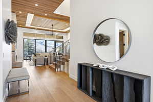 Expansive living area featuring a wood-panel ceiling, large windows with mountain scenery, and light wood-finish flooring
