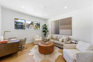 Light wood-finish flooring complements white walls and recessed lighting throughout this versatile space
