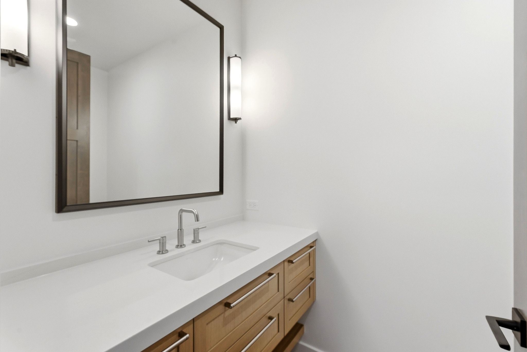Contemporary bathroom vanity featuring a light wood finish, integrated sink, and brushed nickel hardware