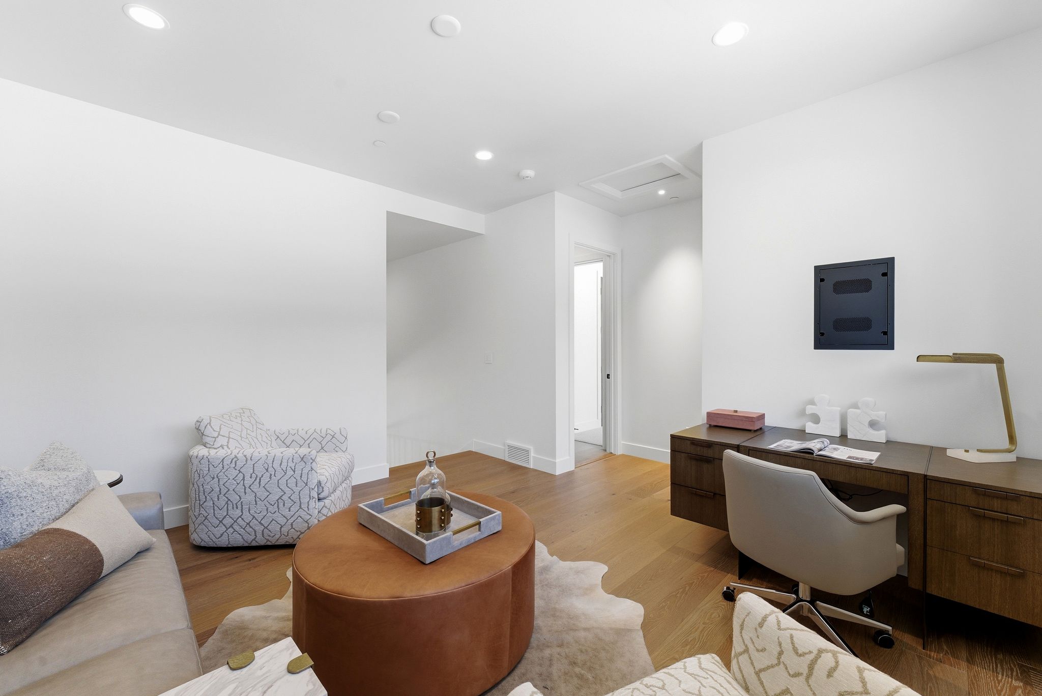 Versatile interior space featuring wood-finish flooring, recessed lighting, white baseboards, and a built-in desk with integrated storage