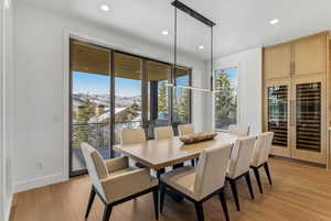 Dining area featuring wood-finish flooring, a linear pendant light fixture, recessed ceiling lights, and built-in cabinetry with integrated wine refrigerators