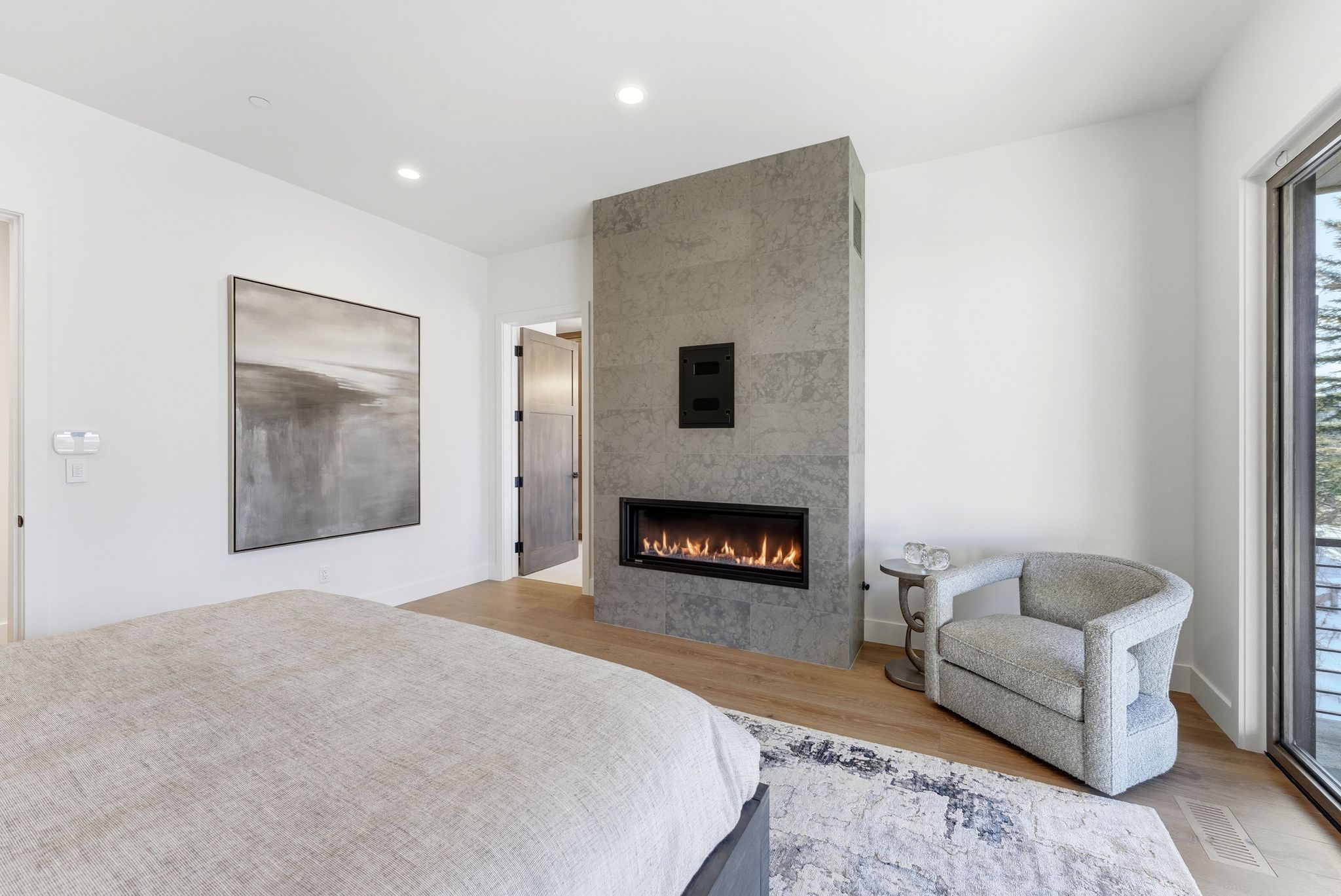 Room featuring a linear fireplace with a stone-finish surround, wood-finish flooring, recessed lighting, and a full-height window