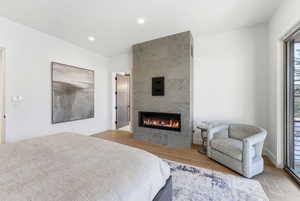 Room featuring a linear fireplace with a stone-finish surround, wood-finish flooring, recessed lighting, and a full-height window