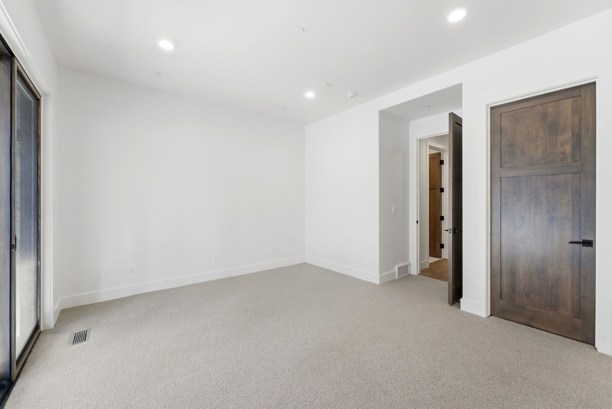 Spacious room featuring light-colored carpeting, white baseboards, and recessed lighting