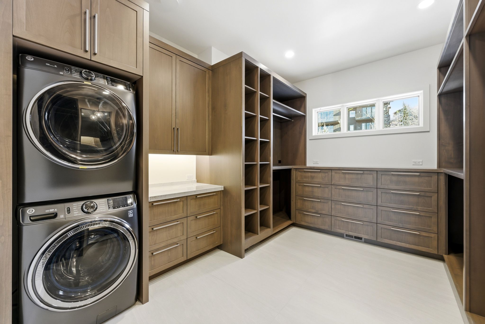 Dedicated laundry area with stacked appliances, complemented by extensive built-in cabinetry and drawers