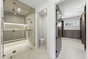 Glass-enclosed shower with a built-in bench, dual shower heads, and an integrated illuminated niche