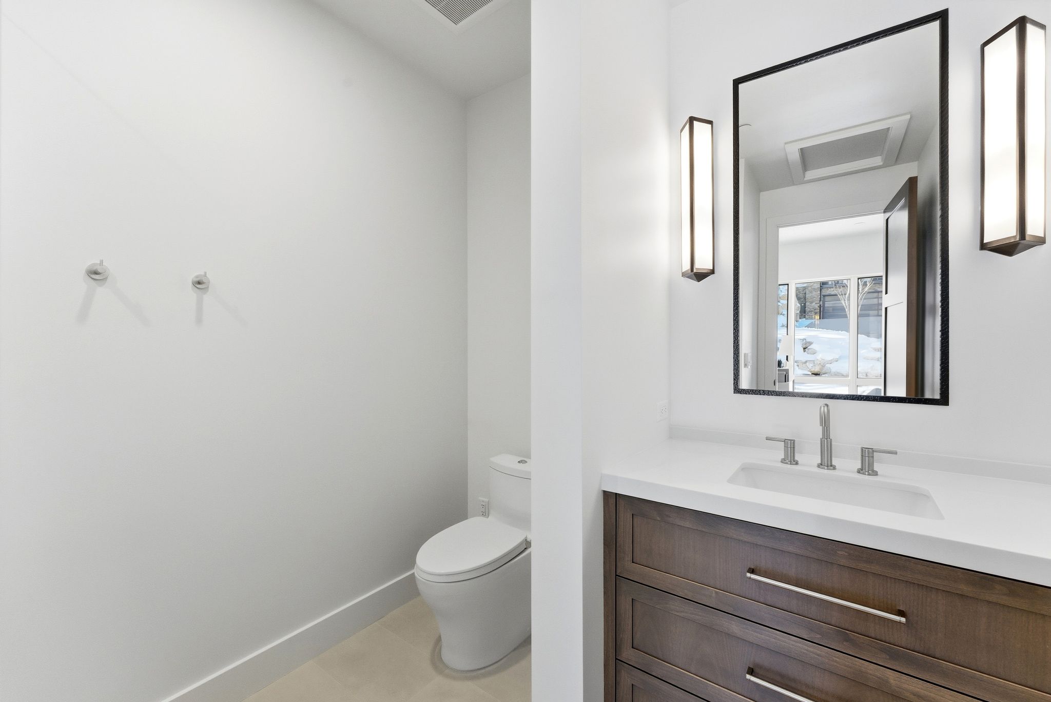 Modern bathroom featuring a wood-finish vanity with a white countertop and integrated sink