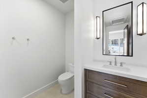 Modern bathroom featuring a wood-finish vanity with a white countertop and integrated sink
