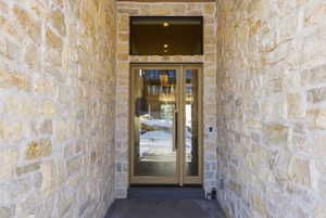 Stone veneer exterior facade with a wood-framed glass entry door and transom window