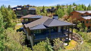 Modern home with a stone and wood siding exterior, featuring a metal roof section and a covered deck