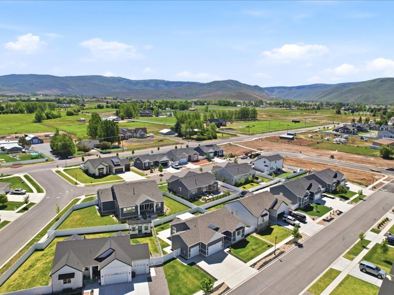 Residential neighborhood featuring a mix of single-family homes with gray and white exteriors, asphalt shingle roofs, and attached garages