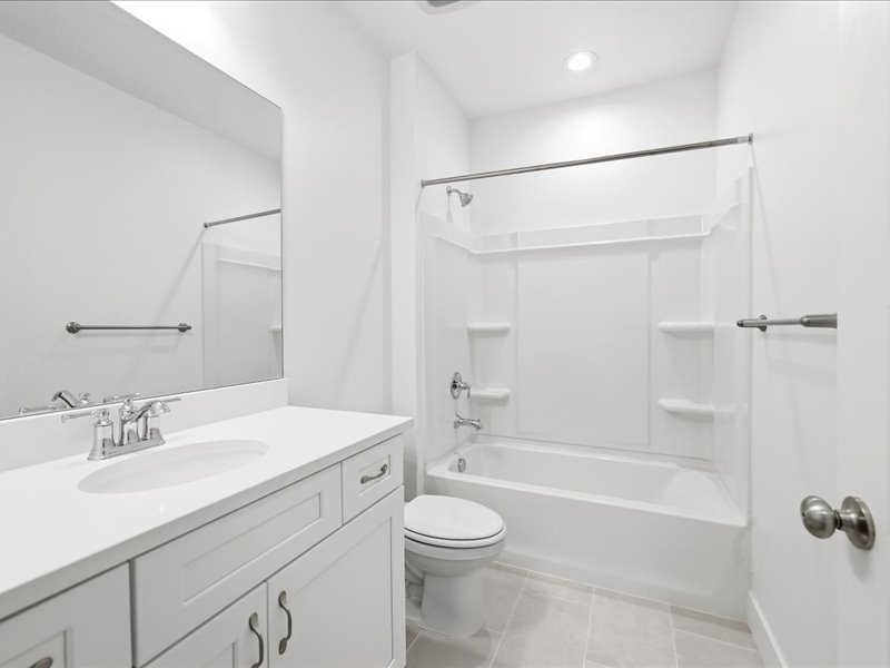 White bathroom featuring a single vanity with an integrated sink, polished chrome faucet, and white cabinet doors with dark hardware