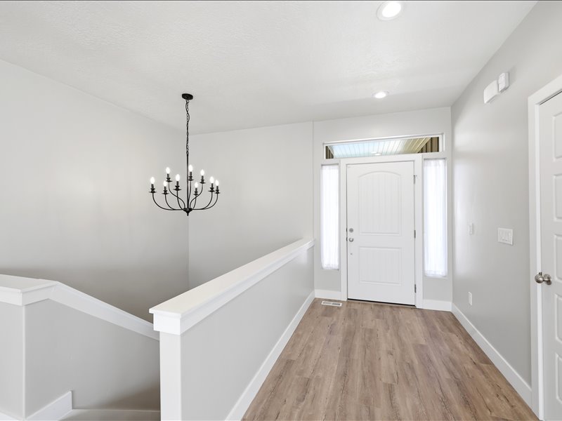 Entryway featuring wood-finish flooring, a white paneled entry door with sidelights and transom window, a black wrought iron chandelier, recessed lighting, and a painted staircase with white trim
