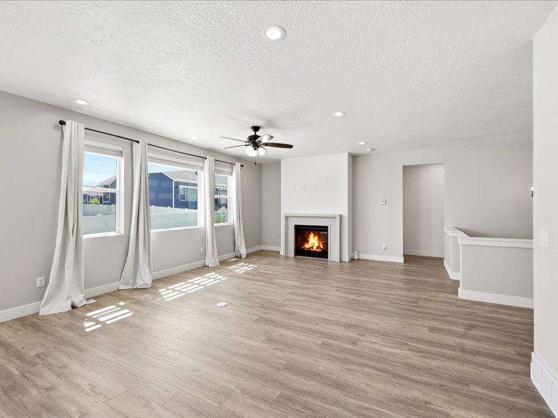 Living space featuring wood-finish flooring, a fireplace with a white mantel, recessed lighting, and a ceiling fan