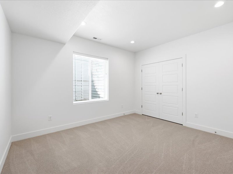 Carpeted room featuring a double-pane window with blinds, white walls, recessed lighting, and a double-door closet with paneling