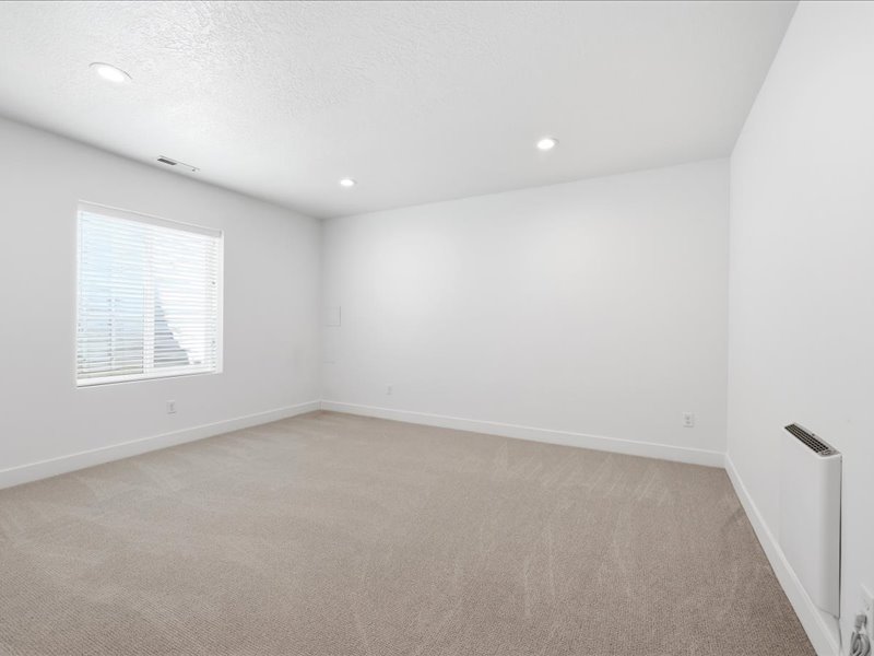 Spacious room featuring neutral carpeting, white walls, and a large window with horizontal blinds