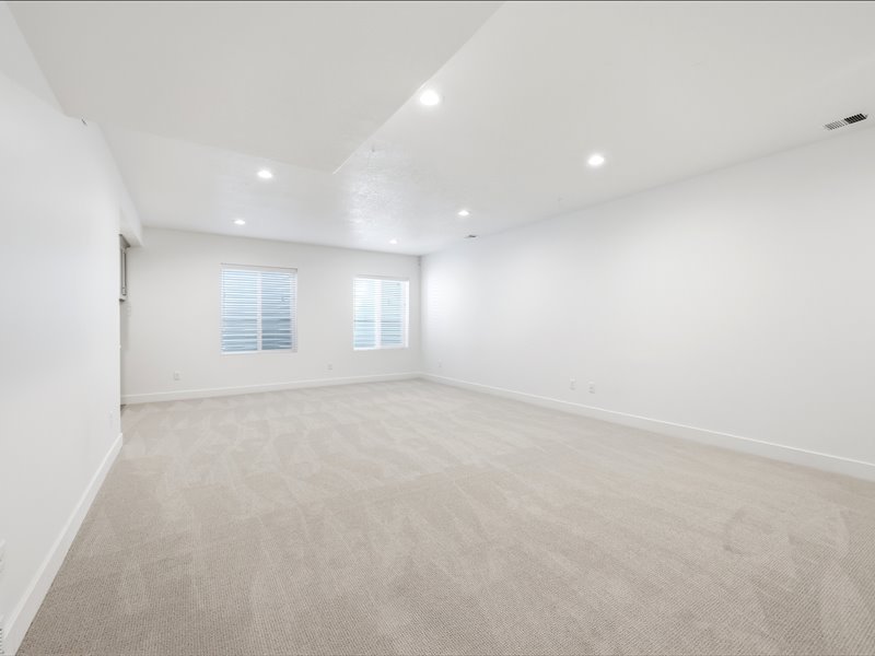 Expansive room featuring plush light-toned carpeting, recessed lighting, and crisp white walls