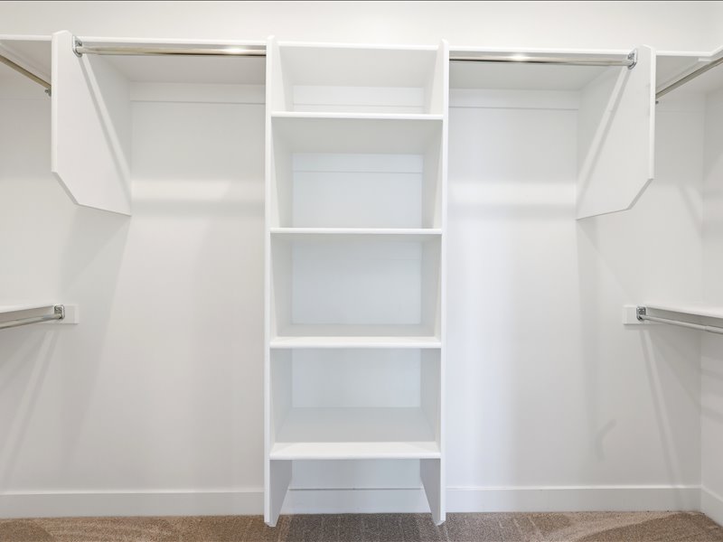 Built-in closet organization system featuring white shelving and chrome hanging rods
