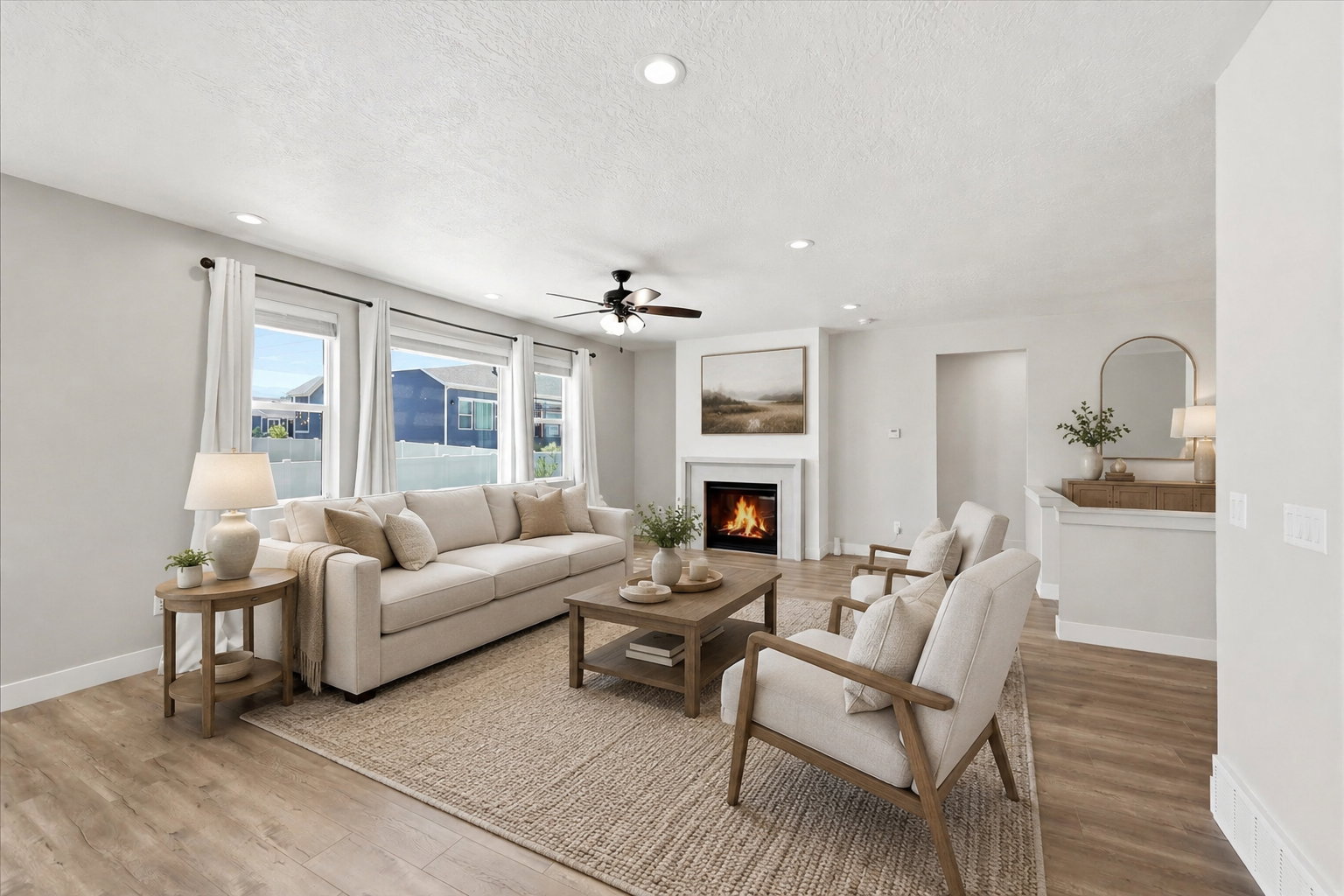 Living space featuring wood-finish flooring, a white mantel fireplace, three large windows, a ceiling fan with light fixture, and recessed lighting