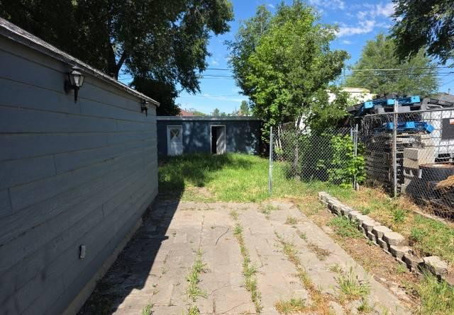Paved concrete walkway with a partial chain-link fence and concrete block retaining wall