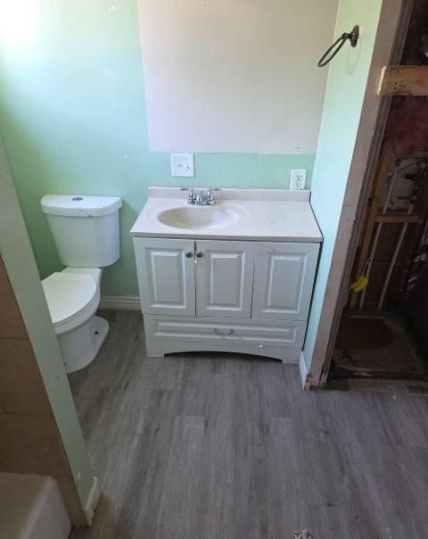 Bathroom featuring a white vanity with integrated sink, chrome faucet, and wood-finish flooring